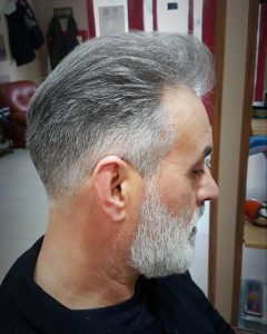 Taper fade with slicked-back hair accompanied with a beard